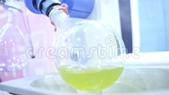 一个圆形的玻璃烧瓶在实验室里旋转实验室助理在烧瓶中接收沉淀物视频的预览图