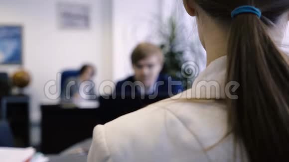 年轻女子肩上的特写办公桌前年轻职员侧肩后视视频的预览图