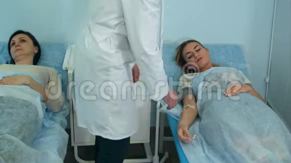 两名女病人躺在医院病房病床上由男医生检查视频的预览图