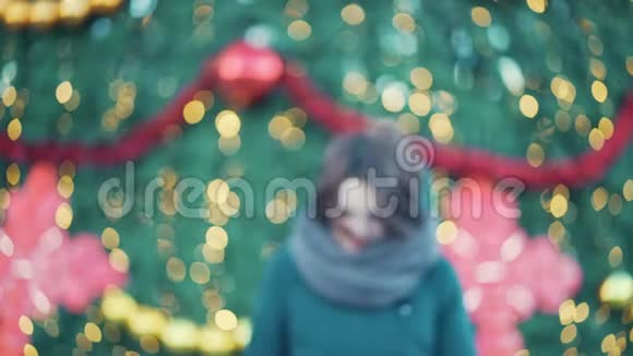 一个美丽微笑的黑发女孩的特写镜头出现在圣诞树附近冬季户外活动视频的预览图