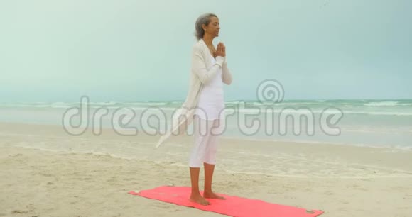 活跃的非洲裔美国老年妇女在海滩上练习瑜伽的侧视图视频的预览图