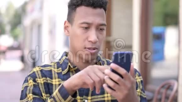 非洲男人在智能手机上庆祝网上成功户外视频的预览图