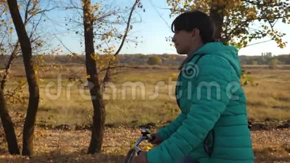 运动少年骑自行车女孩在路上骑自行车旅行一个穿绿色夹克的年轻女孩骑自行车上路视频的预览图