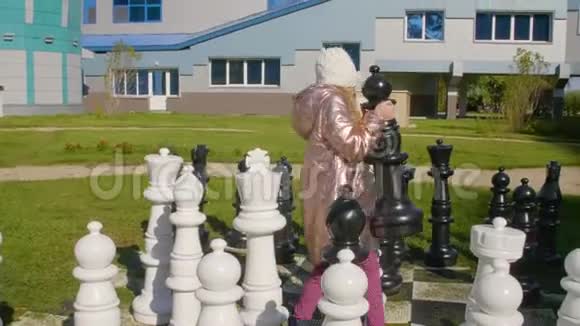 可爱的女孩在与同桌获胜后从棋盘上拿走棋子视频的预览图
