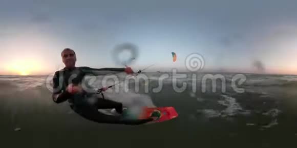 一个穿着潜水服的快乐男人在黎明时从事风筝冲浪一根带相机的自拍棒360视频的预览图