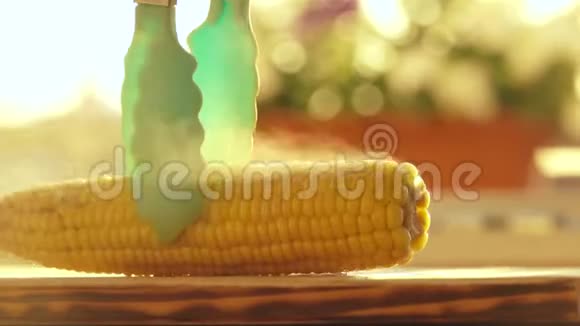 女性的手把一块黄油涂在热玉米上视频的预览图