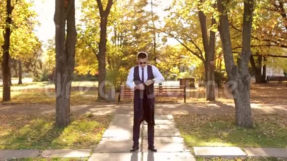 成功的英俊商人在秋天公园穿上夹克视频的预览图