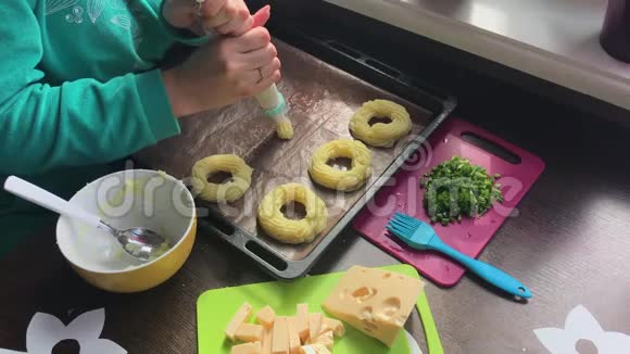 一个女人在烤盘上形成土豆圈借助糕点包奶酪洋葱片和炸蘑菇都在上面视频的预览图