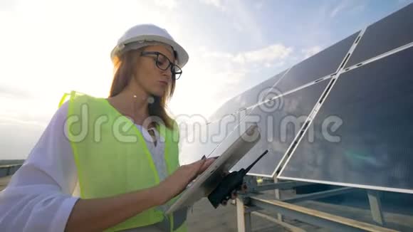 女工程师电工站在屋顶上拿着平板电脑和对讲机视频的预览图