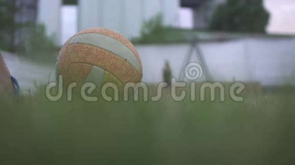 近景排球球在草地上被男足踢向女生对面慢动作视频的预览图