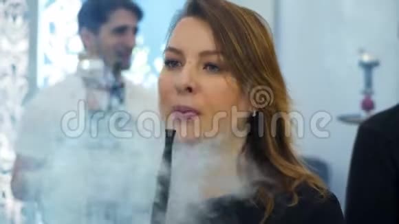 年轻漂亮的女人在夜总会或酒吧里抽烟吸烟的乐趣视频的预览图