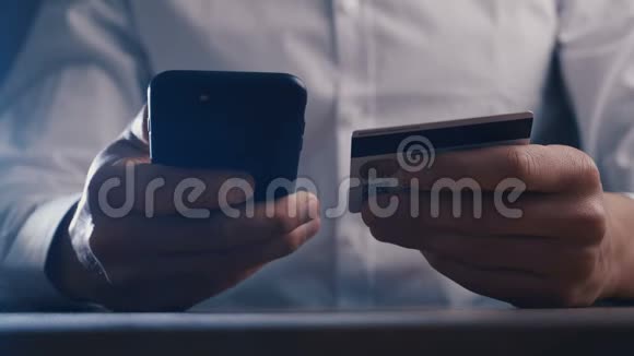 穿白色衬衫的商人使用智能手机在工作场所用信用卡进行网上购物特写镜头视频的预览图