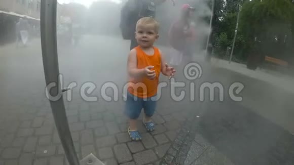 兴奋的男孩在水溅之间在喷泉里玩得很开心城市的夏天视频的预览图