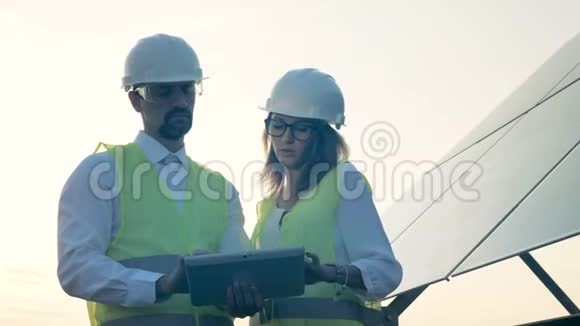 在平板电脑上穿制服的工程师站在太阳能电池板附近替代绿色能源理念视频的预览图