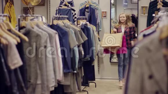 一家服装店里的一位成年美女手里拿着购物袋走到货架前正在寻找新的衣服视频的预览图
