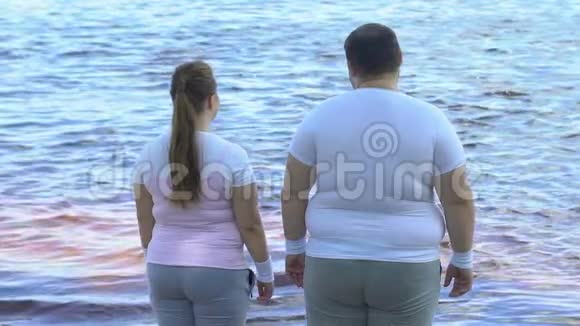 肥胖的女人拥抱她肥胖的男朋友享受平静的湖景视频的预览图