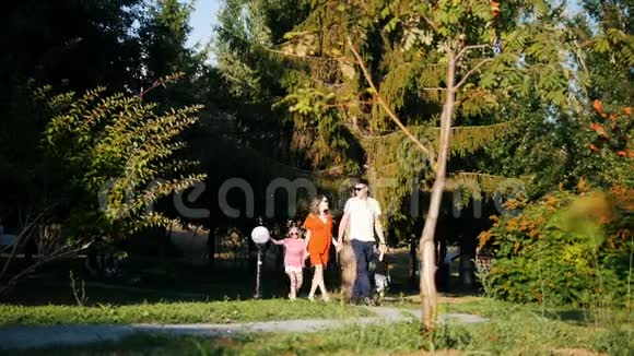 快乐的一家人爸爸妈妈女儿和儿子在阳光明媚的夏日在公园里散步视频的预览图