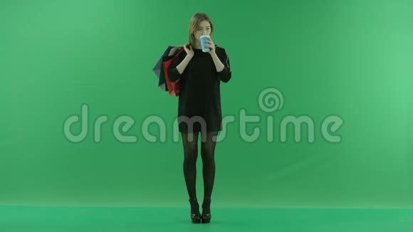 迷人的年轻女子喝茶时肩上背着包颜色关键绿色背景视频的预览图