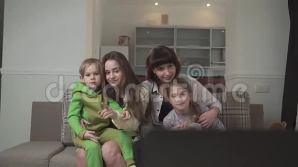 一家人坐在客房的沙发上看电视姐姐和弟弟妹妹在一起视频的预览图
