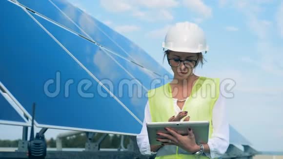 女工程师在平板电脑上打字一位女士站在太阳能电池板附近用平板电脑工作视频的预览图