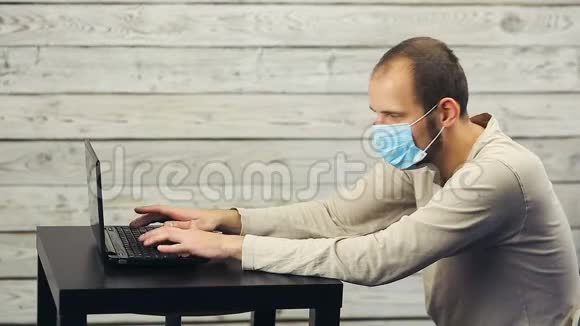 一个戴着医用口罩的男人在电脑里工作咳嗽视频的预览图