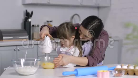 妈妈和有特殊需要的女孩用搅拌机混合面团视频的预览图