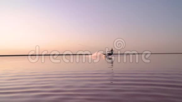 一个人在粉红色的湖上风筝冲浪驶向镜头慢动作视频的预览图