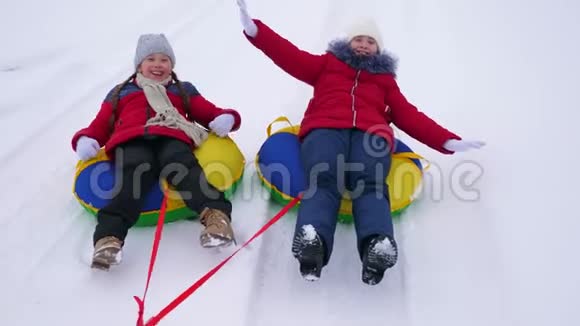 快乐的孩子少年沿着白色的雪道滚在雪盘上笑起来快乐的女孩会在冬天滑雪视频的预览图