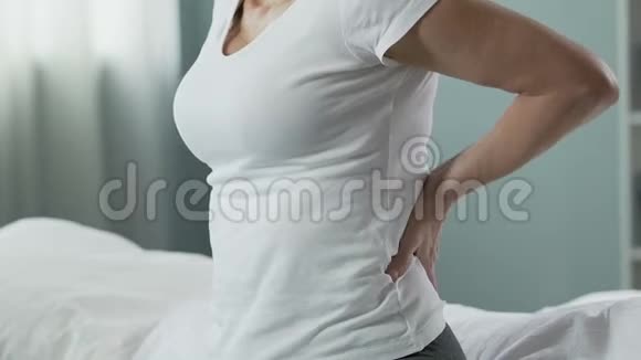 老年女性坐在床上双手按在下背部背疼视频的预览图