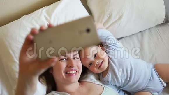 妈妈和宝宝在床上家庭早晨快乐母亲和父母的概念视频的预览图
