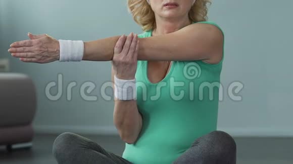 老年妇女盘腿坐着伸展手臂肌肉抽筋锻炼身体视频的预览图