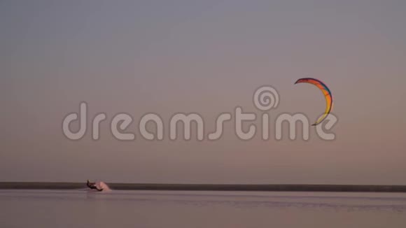 一个孤独的基特在湖边管理一只橙色的训练风筝一副平静的样子视频的预览图