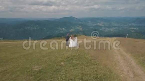 新郎和新娘一起在山上散步空中无人机射击视频的预览图