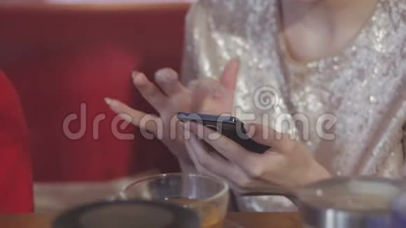 美丽的年轻女性手的特写滚动智能手机上网在咖啡馆和一杯咖啡在桌子上视频的预览图