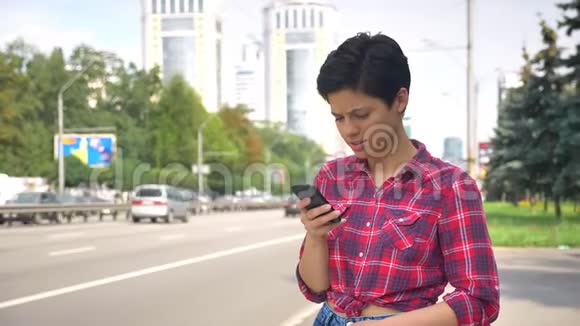 一位留着黑色短发的年轻女子打电话等出租车或找公车微笑着快乐的女性视频的预览图