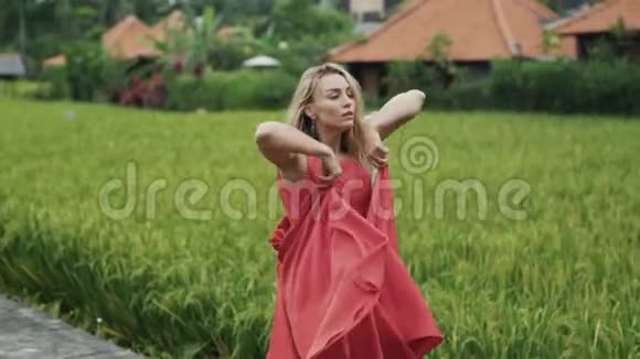 在米台上一个年轻漂亮的女孩穿着一件红色连衣裙带着一个郁郁葱葱的吉普赛人的慢镜头拍摄中跳舞视频的预览图