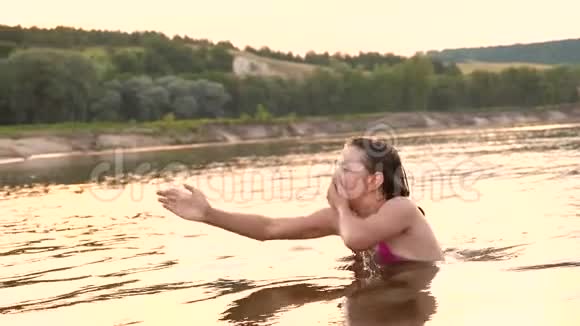 穿着泳衣的年轻快乐女孩潜入水中在夏天的晚上大笑海滩季节慢动作视频的预览图