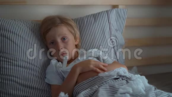 一个带体温计的生病的小男孩在床上被超慢镜头拍摄婴儿流感概念视频的预览图