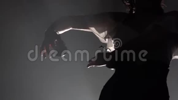 女孩手里拿着蓖麻子跳舞从后面的光烟雾背景慢动作视频的预览图