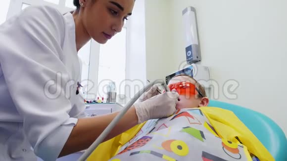 年轻的女牙医敏感地仔细地对待一个小男孩的牙齿视频的预览图
