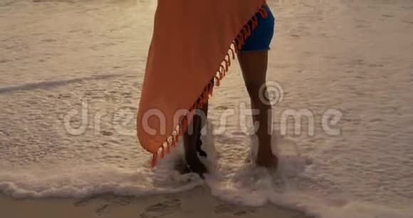 海滩上用毯子包裹的非裔美国人夫妇的侧面景色视频的预览图