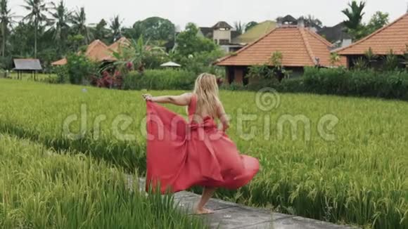 一个孤独的年轻舞者穿着一件红色的长绸连衣裙沿着米台走着跳起她那条流动的裙子这条裙子视频的预览图