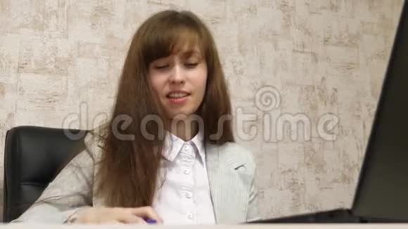 漂亮的女孩坐在办公室的椅子上用bloknot说话和做笔记青年女企业家视频的预览图