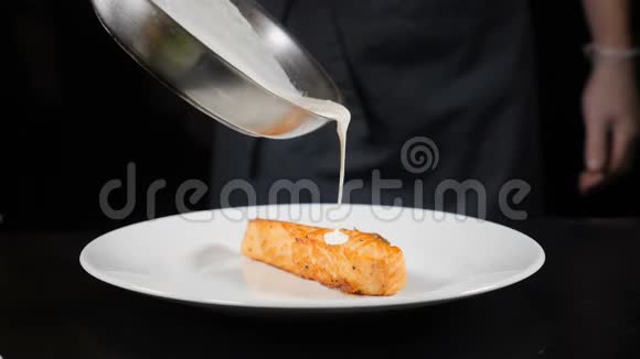 美味的菜肴厨师带着手套慢慢地把刚做好的奶油酱倒在油炸鳟鱼片上餐厅食品视频的预览图