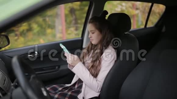 一个年轻的女人和她十几岁的女儿在一起妈妈有车女儿用智能手机视频的预览图