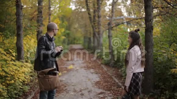 男摄影师在秋公园拍摄少女少年的照片视频的预览图