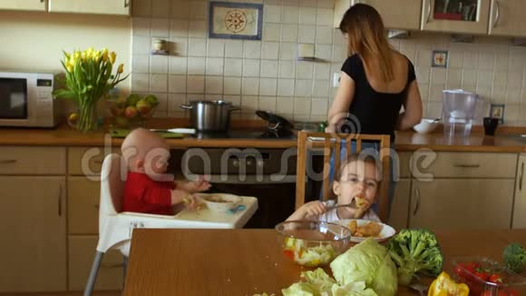女孩同时在厨房准备晚餐寻找两个孩子一个男孩和一个女孩家庭主妇视频的预览图