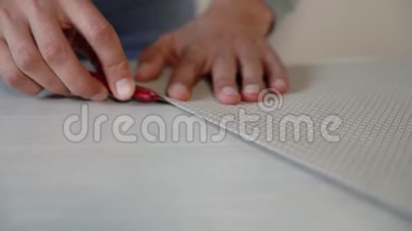 特写男手用文具刀在桌上剪下弯曲的墙纸卷视频的预览图