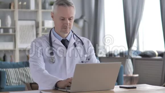 在笔记本电脑上工作的高级医生视频的预览图