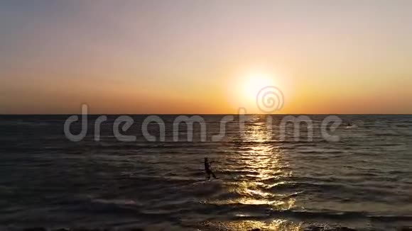 日落时分三名赤鸢的冲浪者迅速地从空中滑过海面视频的预览图